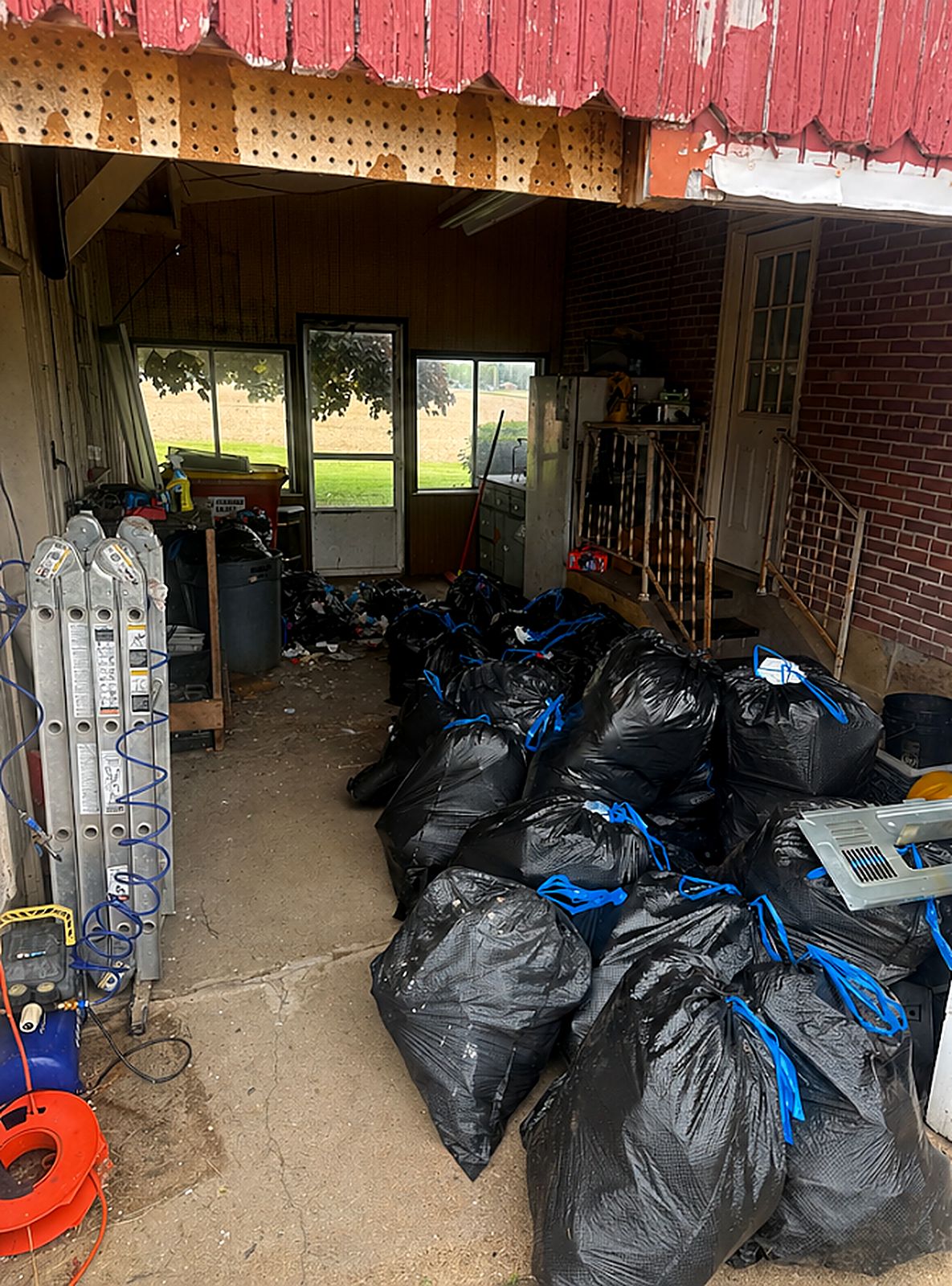 Before: covered garage area filled with trash bags, cleared to bare concrete